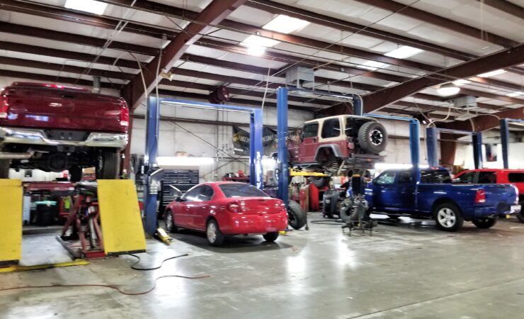 A team of auto mechanics in a bustling garage, working together on various car repairs and maintenance tasks.