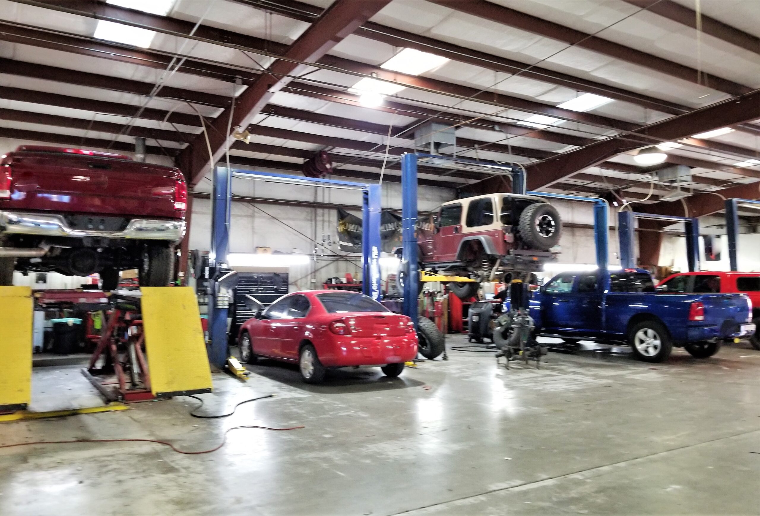 A team of auto mechanics in a bustling garage, working together on various car repairs and maintenance tasks.