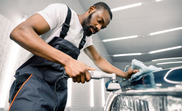 A professional car detailer uses a dual-action polisher and polishing compound to remove swirl marks and imperfections from a car's paint.