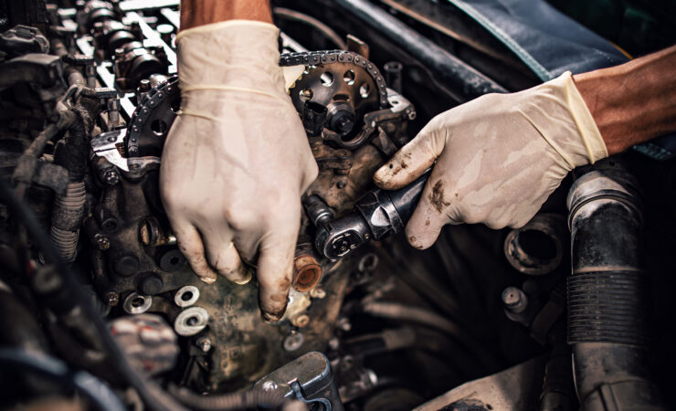 A vintage car is being restored in a well-lit garage, with tools and parts scattered around.