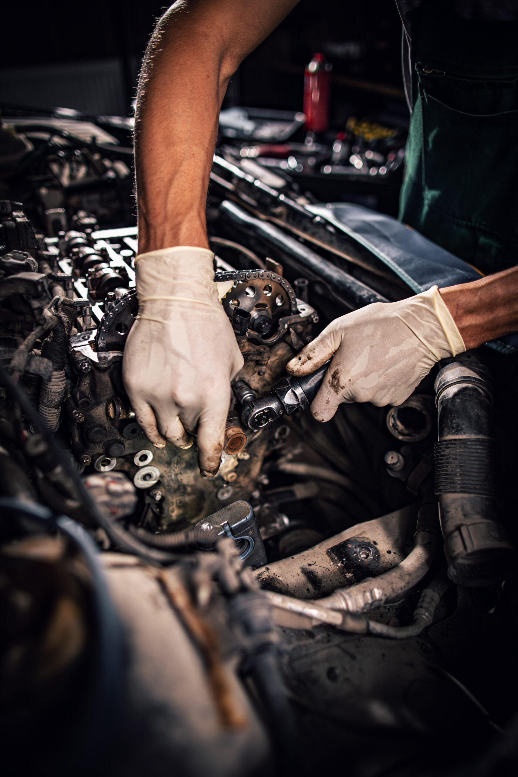 A vintage car is being restored in a well-lit garage, with tools and parts scattered around.