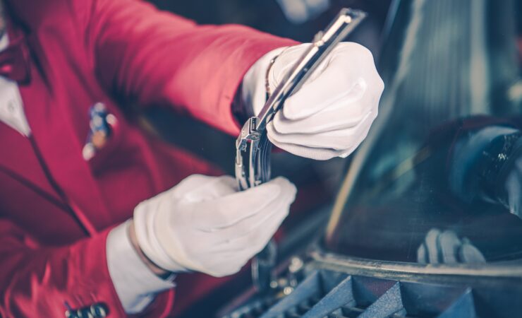 A mechanic's hands, holding a vintage carburetor, carefully install it into the engine bay of a classic car.