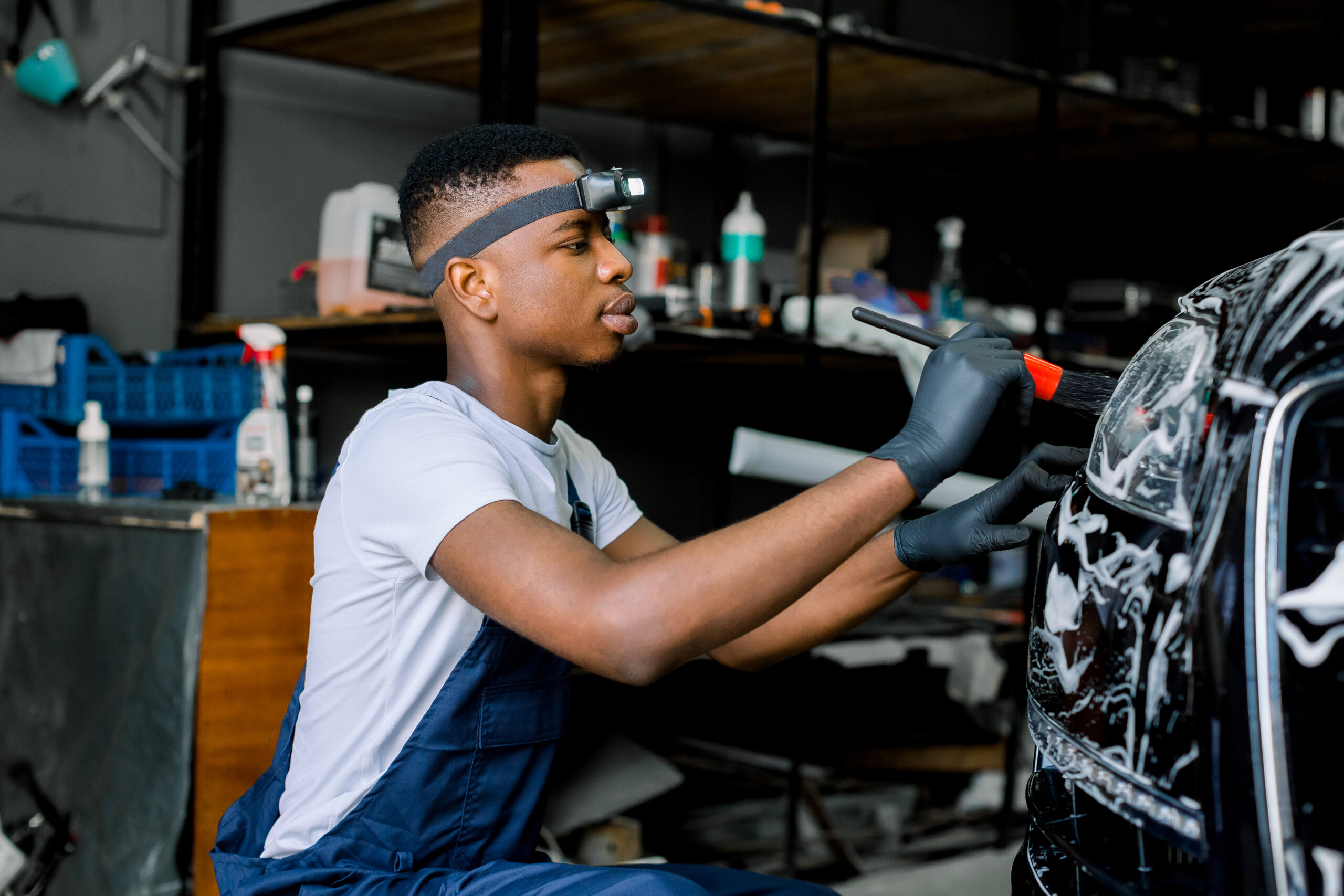 A close-up photo of a young African man wearing protective gloves, his hands holding a specialized tool with a determined expression on his face.