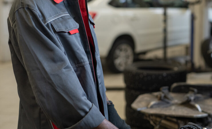 A technician in a blue jumpsuit reaches for a wrench from a tool chest.