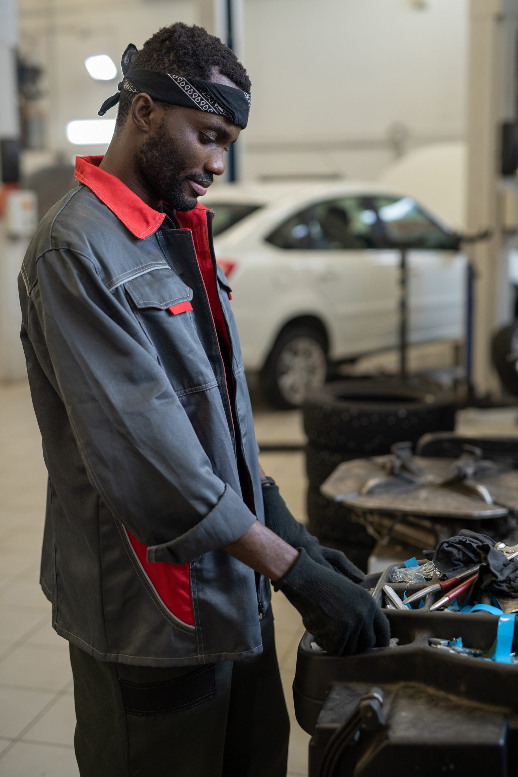 A technician in a blue jumpsuit reaches for a wrench from a tool chest.