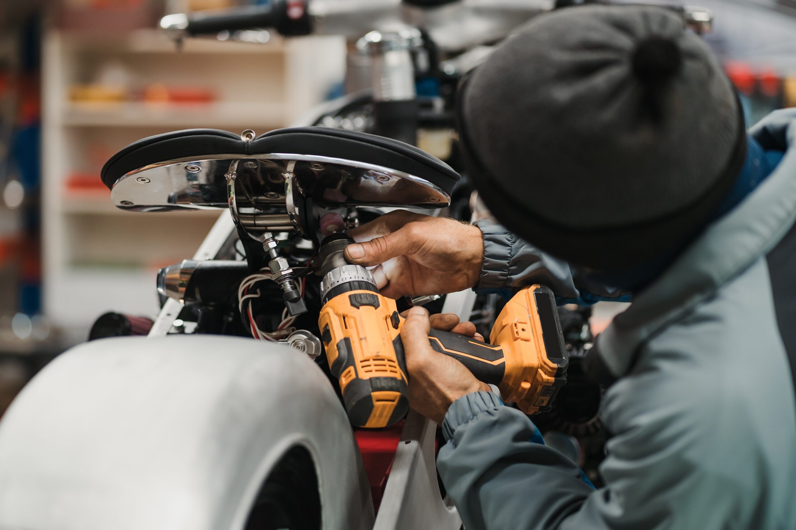 A focused mechanic, clad in a leather jacket and jeans, leans over a motorcycle in a well-lit workshop, carefully adjusting the carburetor.