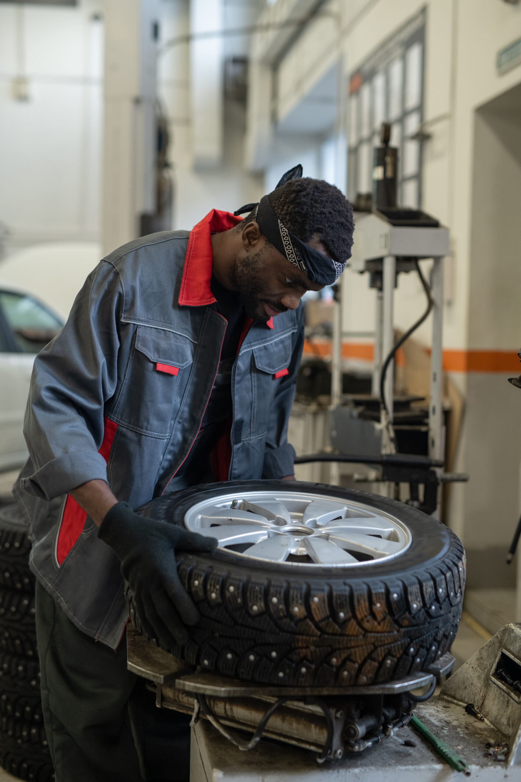 A mechanic in a blue jumpsuit carefully examines a tire's tread and sidewall, selecting the right fit for a customer's vehicle.