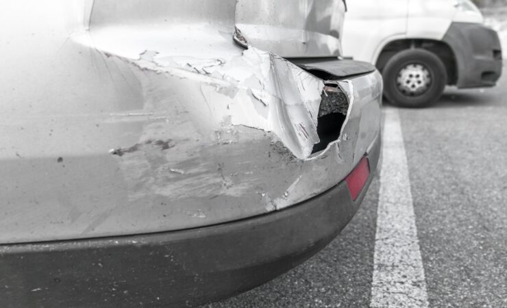 A gray car with significant rear-end damage from a car accident.