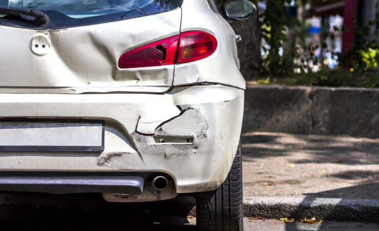 A white car with extensive damage to the rear bumper and trunk after a collision.