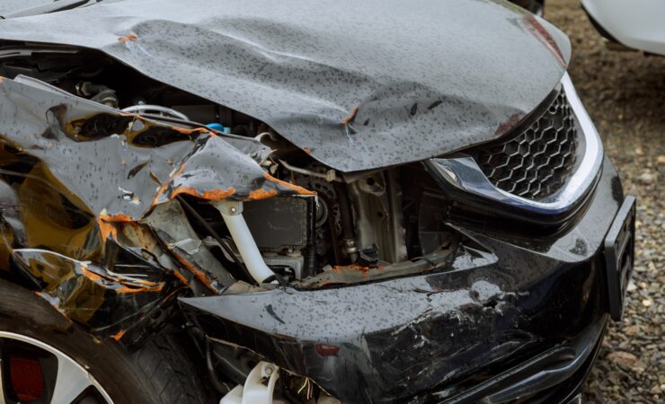 A close-up of a car's front end, crumpled and mangled from a collision.