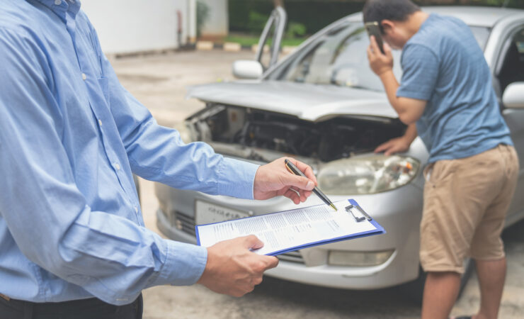 An insurance officer, pen in hand, meticulously fills out an insurance claim report on a clipboard.