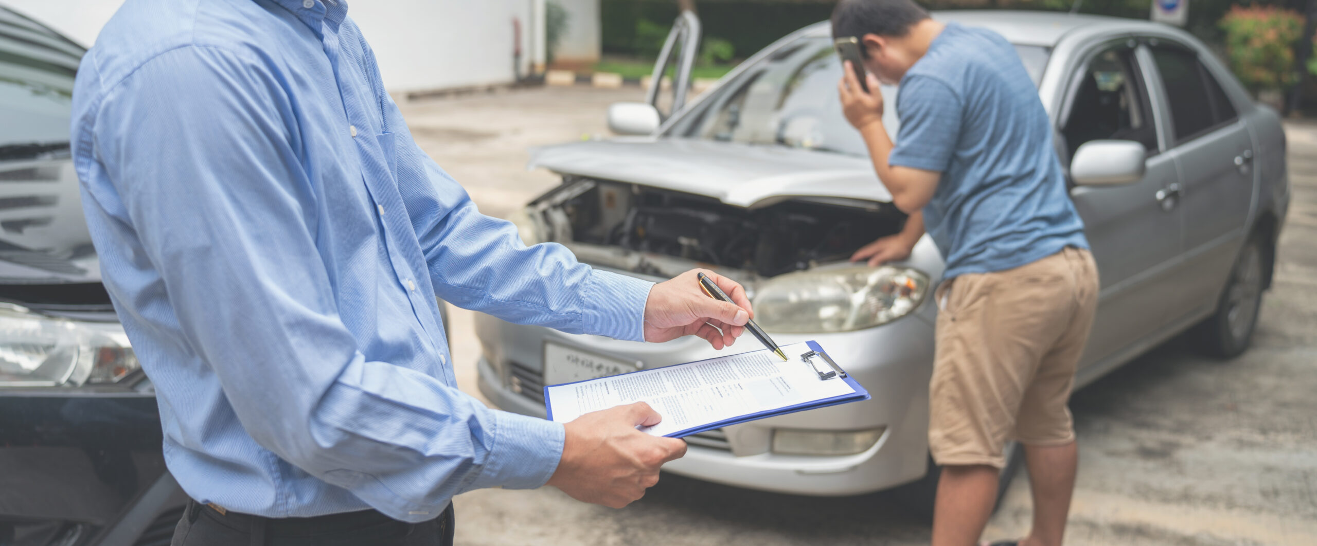 An insurance officer, pen in hand, meticulously fills out an insurance claim report on a clipboard.