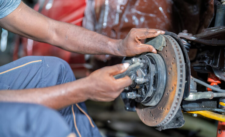 A mechanical man, its metallic body gleaming, focuses intently as it uses a wrench to repair a car.