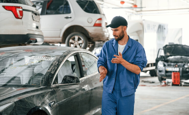 A mechanic in a garage, working on a dirty car.