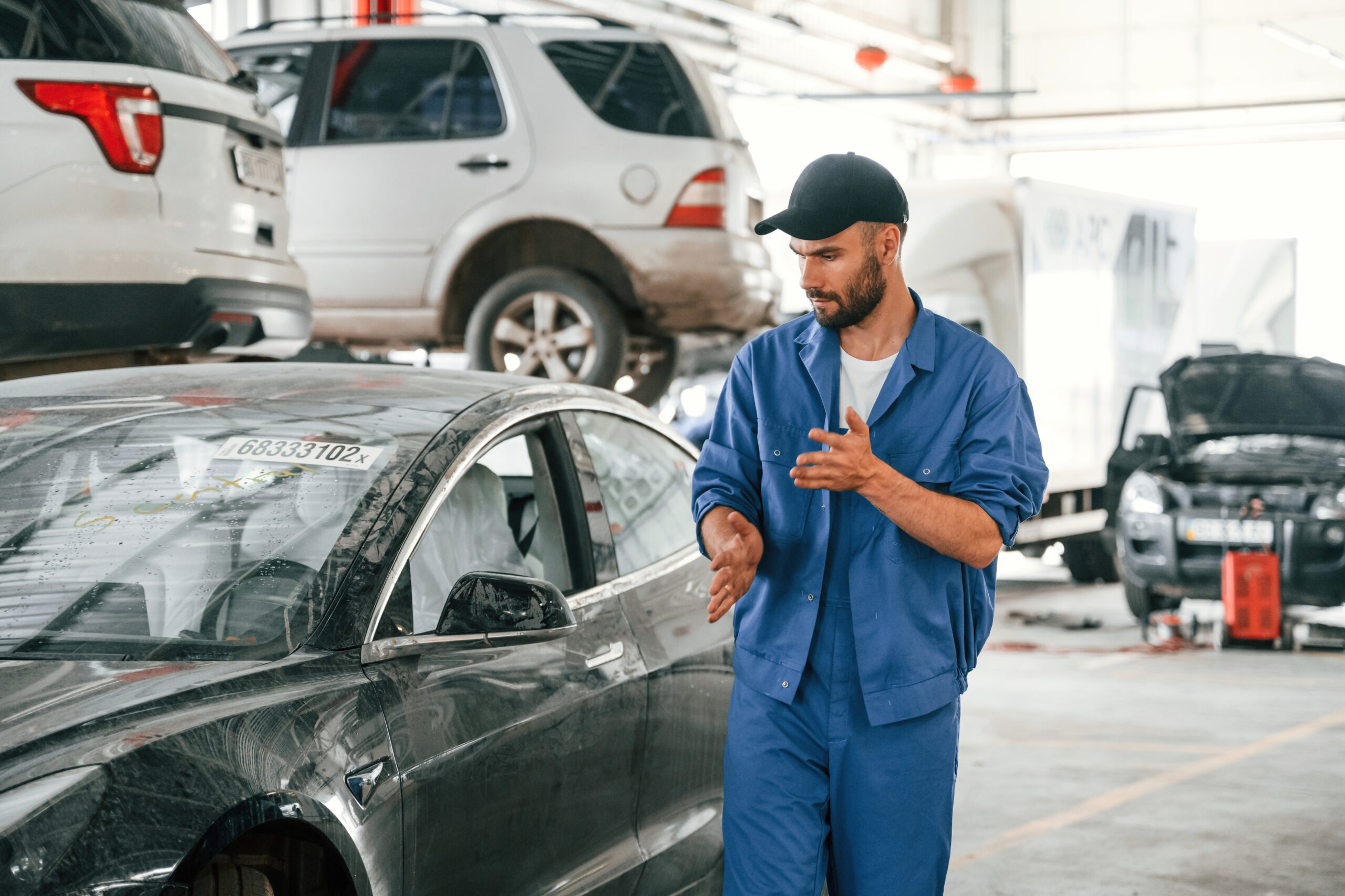 A mechanic in a garage, working on a dirty car.