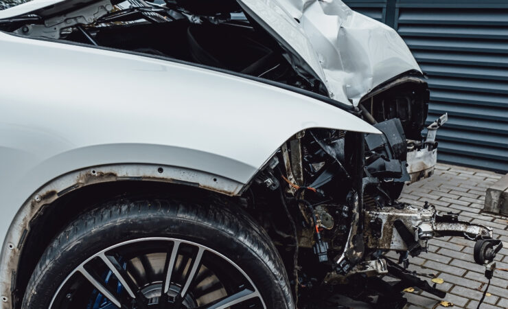 A white car that has been totaled in an accident after colliding with a lamppost.