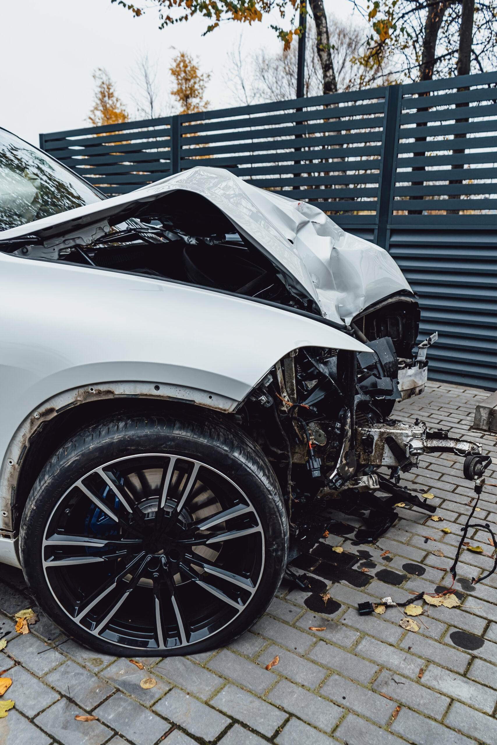 A white car that has been totaled in an accident after colliding with a lamppost.